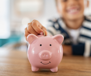 Child placing money into piggy bank