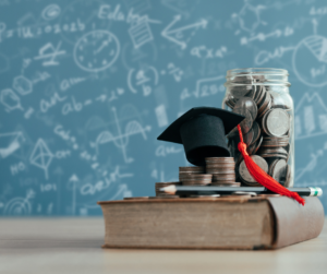 A graduation cap in a classroom next to a jar of coins, meant to symbolize student debt