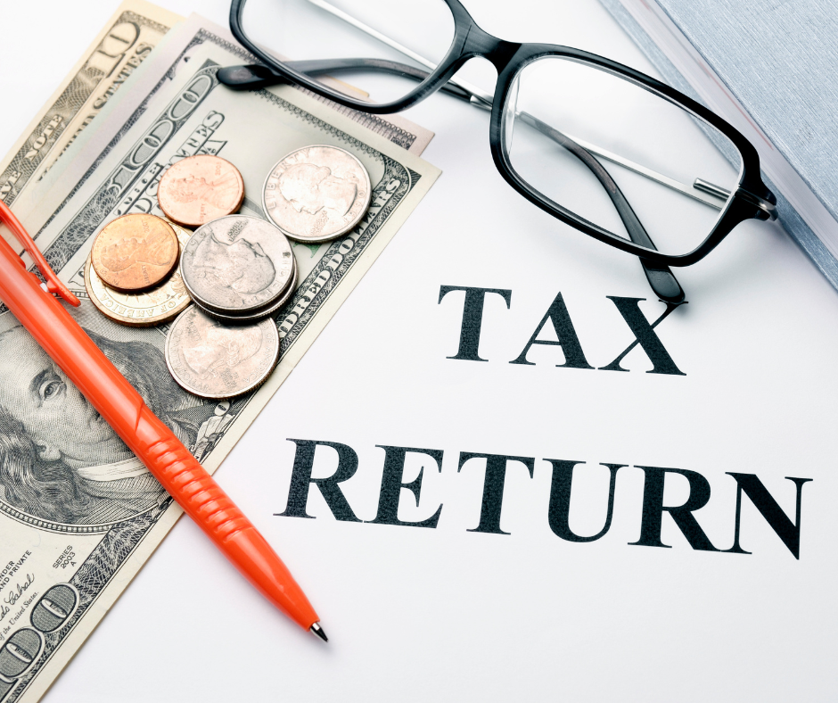 Paper with tax return wrote on it. Glasses money and pen are laying on top.